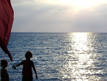enjoy the sunset on lonely beach while the childeren have fun on the beach